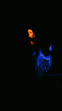 a woman in a blue dress standing in the dark