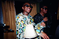 a man in a colorful shirt is standing next to a lamp